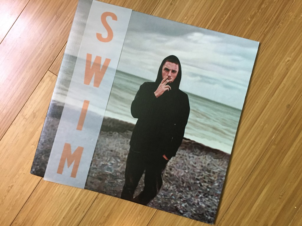 Swim by Die! Die! Die! album on a wood floor